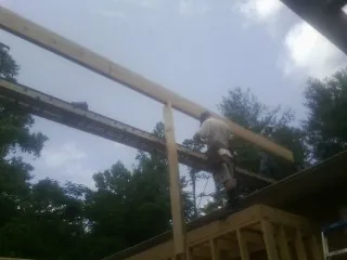 Carpenter setting a ridge beam over a new addition frame — Ice Dam Removal by Roofing Brothers in Wauregan