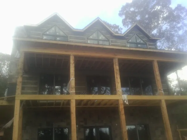 Dormers and porch framing on a large log home under construction — Roof Coating work by our crew in Wauregan