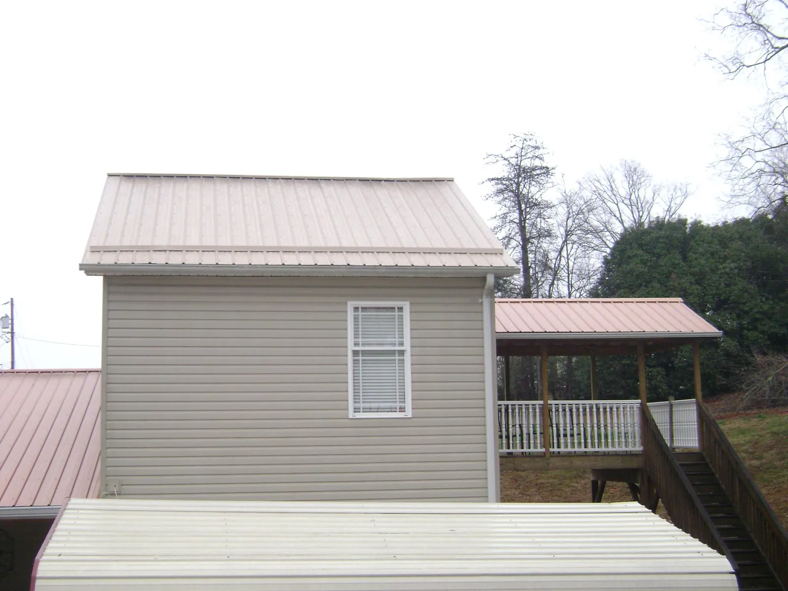 Tan metal roofs on a two story addition and attached porch, from a Roof Replacement job in Wauregan