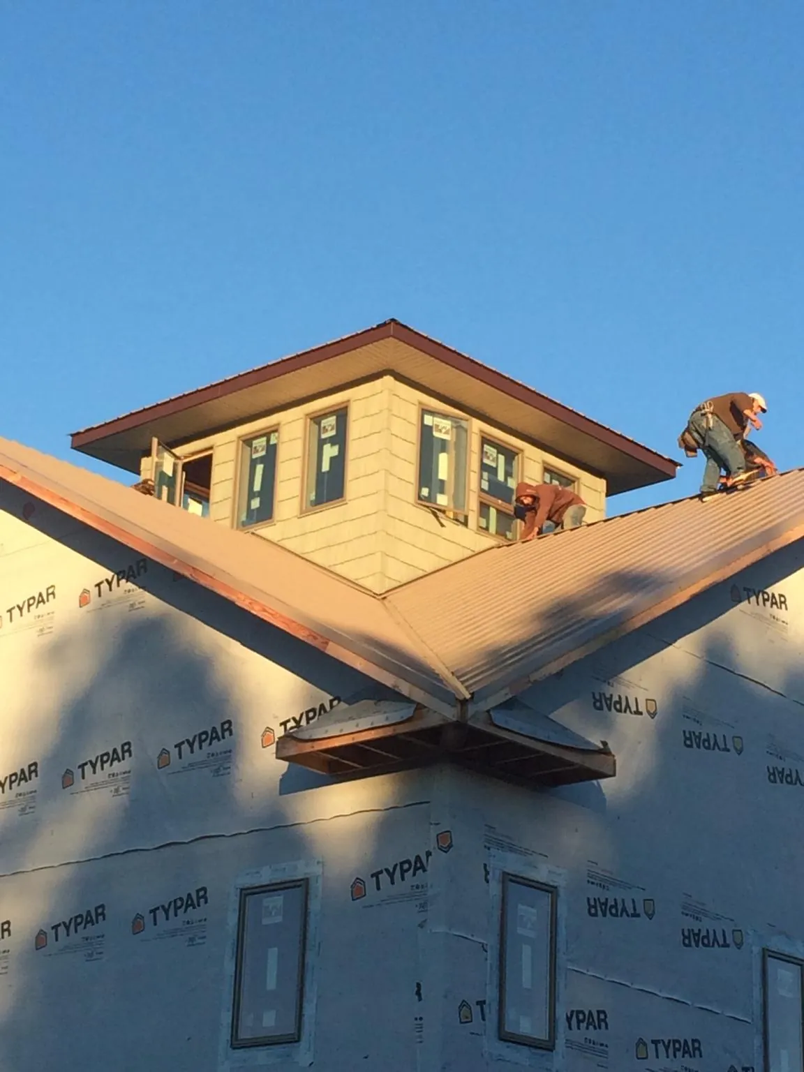 Roofers working around a rooftop cupola on a new metal roof at sunset — Roof Waterproofing in Wauregan by Roofing Brothers